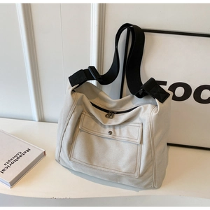 Detailansicht der cremefarbenen Segeltuchtasche mit Fronttasche und schwarzem Schultergurt