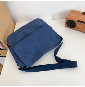 Nahaufnahme der dunkelblauen Canvas-Umhängetasche mit Klappentasche auf weißem Tisch