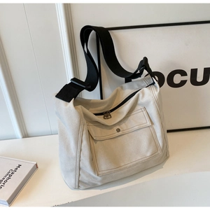 Detail of minimalist canvas crossbody bag with front pocket and adjustable black strap