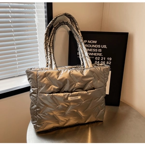 Détail du sac fourre-tout argenté matelassé avec surpiqûres et étiquette mode discrète
