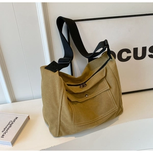 Detail view of mustard yellow canvas messenger bag with white stitching and black metal zip
