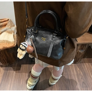 Detail of black baseball-style crossbody bag with plush bear charm and gold logo