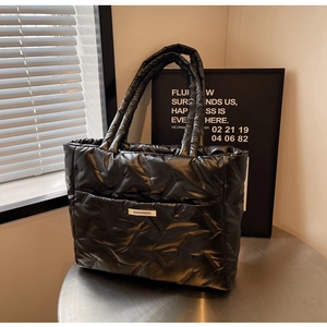 Détail du sac cabas matelassé noir brillant avec texture piquée et logo de mode