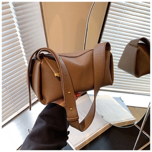 Detail of a brown leather pillow bag featuring fine lychee texture and gold metal hardware