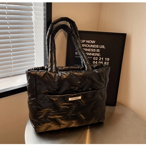 Détail du sac cabas matelassé noir avec étiquette de mode et texture brillante