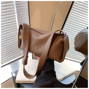 Detail of brown litchi pattern leather cylinder bag with wide strap and gold hardware
