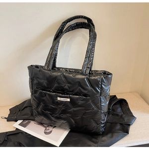 Détail du sac cabas matelassé noir avec texture en V et étiquette de mode