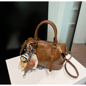 Detail view of vintage brown boston bag with plush bear charm and metallic brand logo