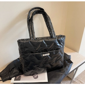 Détail du sac cabas matelassé noir avec motif en V et étiquette de mode sur le devant