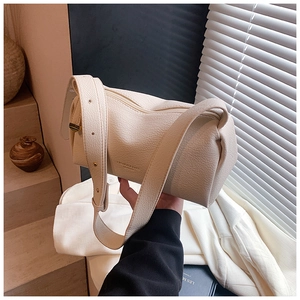 Detail of lychee pattern leather on beige cylinder shoulder bag with a wide strap