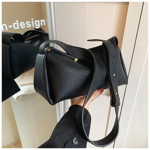 Detail of minimalist black pebbled leather pillow bag with gold rivet strap decoration