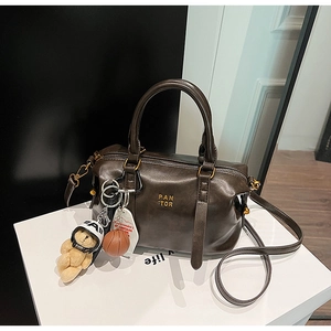 Detail of dark brown vintage Boston bag with plush bear charm and golden logo branding