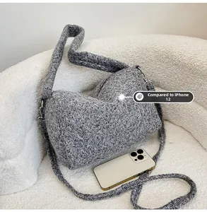 Grey knitted crossbody tote bag shown next to an iPhone 12 for size comparison