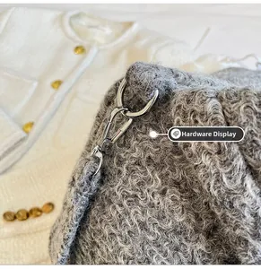 Detailed view of silver metal lobster clasp and soft grey curly faux fur texture