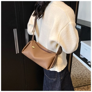 Brown lychee-grain leather shoulder bag with gold hardware worn by a model in casual attire