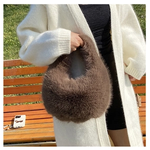Detailansicht der braunen Plüschtasche kombiniert mit weißer Strickjacke im Herbst