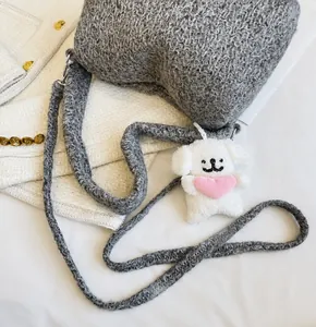 Detail view of the gray knit shoulder strap with a cute white puppy plush charm