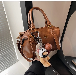 Detail of a brown vintage Boston bag with a teddy bear charm and gold hardware