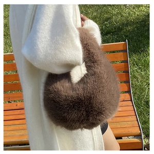 Braune Plüschhandtasche aus Kunstpelz mit weicher Textur von einem Model draußen getragen
