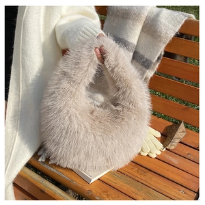 Detailansicht einer weichen beigen Plüschhandtasche auf einer Holzbank mit Winterdeko