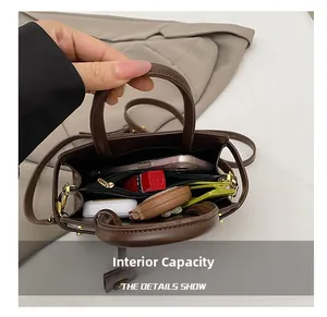 Détail de la capacité interne du sac bandoulière en cuir marron avec des objets