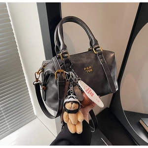 Close-up of dark grey Boston bag with PAN'TOR logo and a cute teddy bear charm