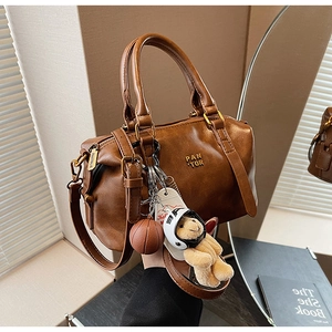 Close-up of vintage brown leather bag with golden hardware and cute bear charms