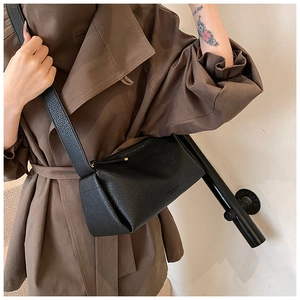 Detail of black lychee grain leather crossbody bag with embossed logo and fine strap