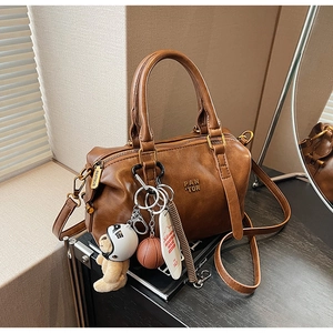 Detail of vintage brown leather Boston bag with embossed logo and plush bear accessory