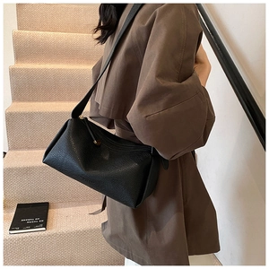Lifestyle shot of a black pebbled leather crossbody pillow bag worn by a model