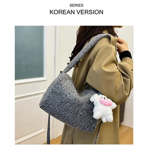 Detail of grey knitted tote bag with a cute white plush doll hanging from the strap