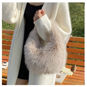 Nahaufnahme der flauschigen Kunstfell-Handtasche in Beige, am Arm im Freien getragen