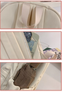 Detail of cream backpack showing reinforced top handle and hidden anti-theft zipper pocket