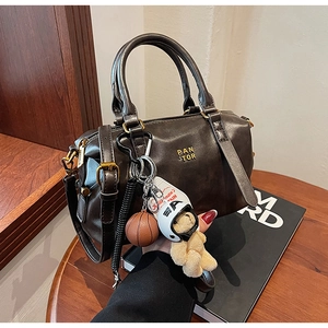 Detailed close-up of retro brown Boston bag with Pan Tor logo and bear pendant charms