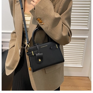 Détail d'un sac à main noir en similicuir mat avec finitions dorées et logo de marque