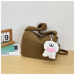Detail of a brown fuzzy lamb wool tote bag with a white plush dog charm on a wooden table