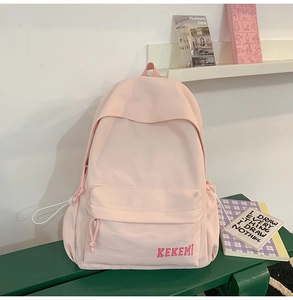 Close-up of a minimalist light pink student backpack with KEKEMI logo on a green bench