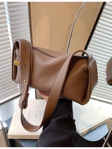 Brown lychee leather shoulder bag with rounded design and gold hardware shown in warm light