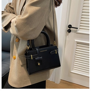 Gros plan sur un sac en cuir noir avec détails dorés et marquage logo MIKAXIQI