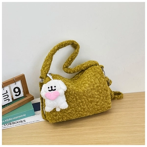 Detail of moss green fuzzy tote bag with cute white puppy plush charm on wooden table