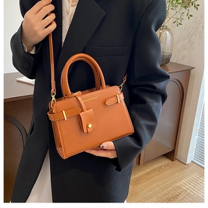 Sac à main en cuir marron avec détails dorés porté par un mannequin en intérieur