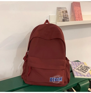 Detail of burgundy nylon backpack featuring white KEKEMI logo on casual side drawstring bag