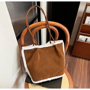 Detail of suede tote bag with white shearling trim hanging on a wooden chair