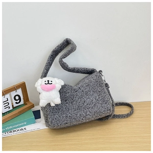 Close-up of grey wave-textured knit shoulder bag with cute white puppy plush charm