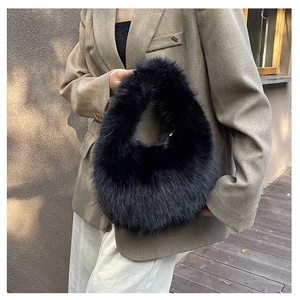 Draußen-Aufnahme einer schwarzen Kunstfell-Handtasche mit Ringgriff und Gold-Zipper