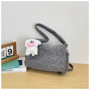 Detail of gray knitted shoulder bag with a cute white puppy charm on a wooden table