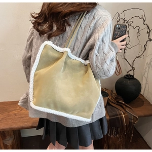 Detail of khaki suede tote bag with white shearling trim shown on a person’s shoulder