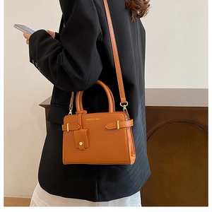 Vue latérale d'un sac bandoulière vintage marron caramel avec poignée et finitions dorées