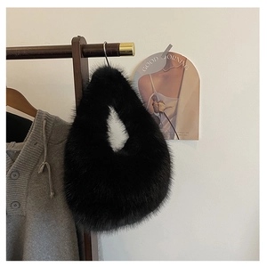 Detailaufnahme der weichen schwarzen Kunstfell-Textur einer Plüschtasche an einem Holzbügel