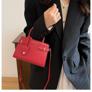 Gros plan d'un sac à main en cuir rouge avec boucle dorée et détails du logo